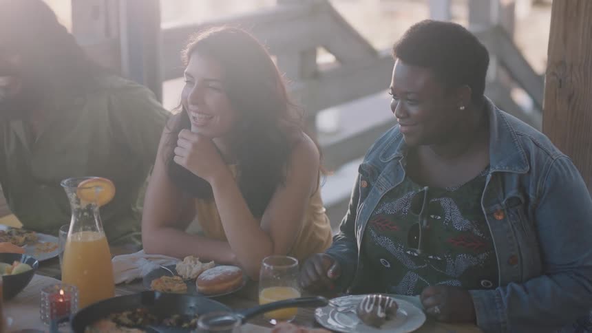 Group of happy friends talking and laughing sitting at a table in a restaurant