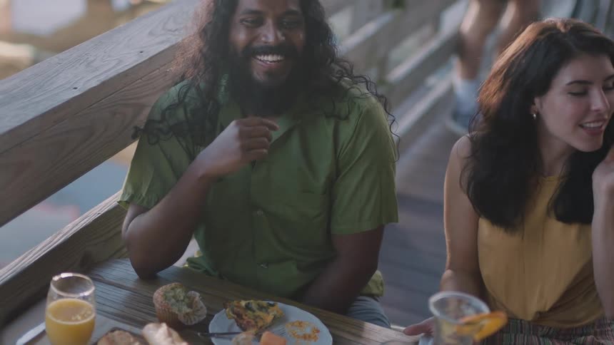 A man and woman sitting at an outdoor restaurant table with friends talking and laughing