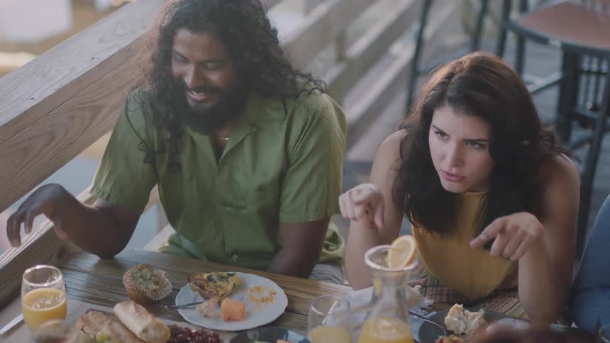 A woman tells a story to her friends over drinks and brunch on a patio