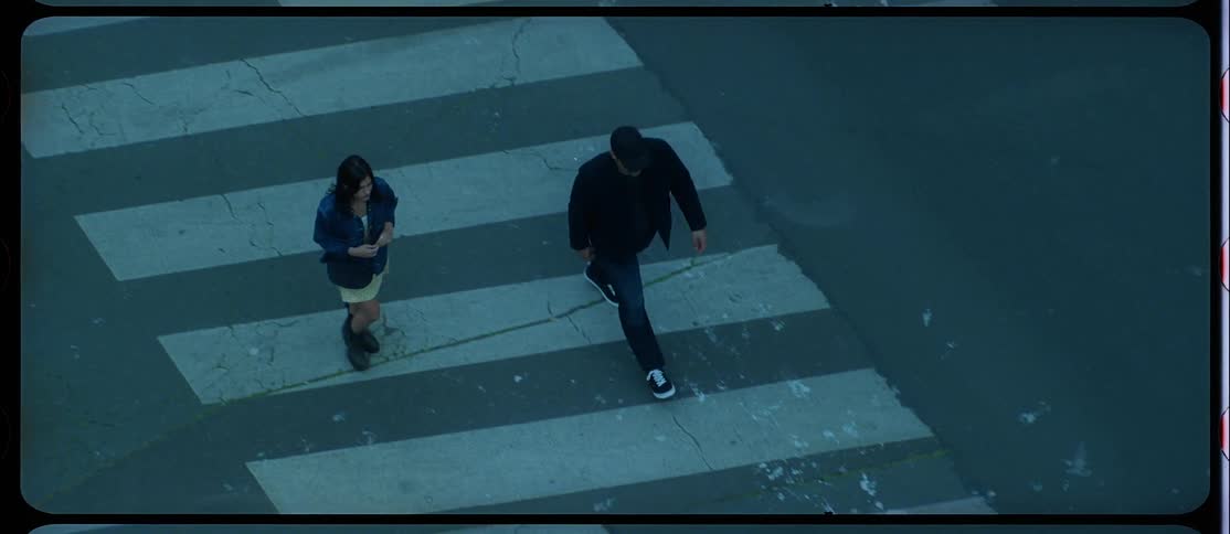 Man and woman cross intersection walking along crosswalk