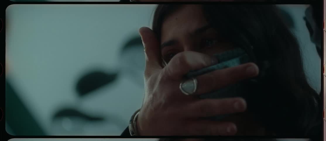 A woman with a mask in a room with a man grabbing her face from behind