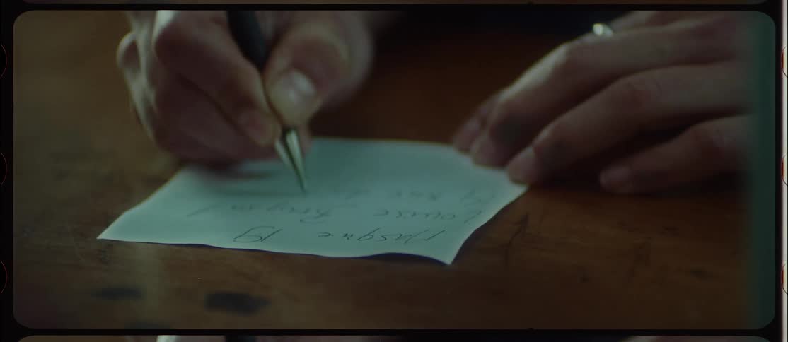 Person wearing ring writes on piece of paper before handing it across counter to another person