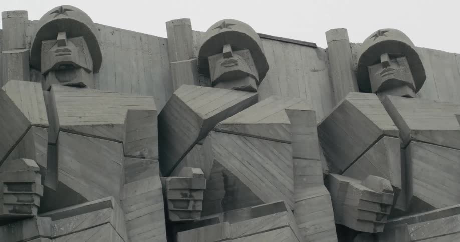 Gray blocking monument of soldiers stands under pale blue sky
