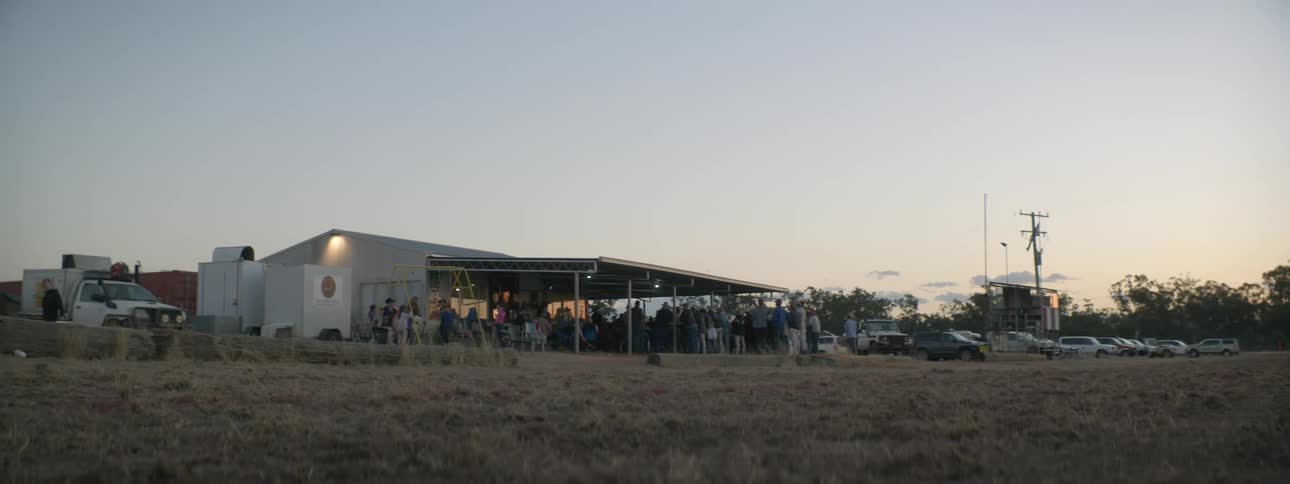 A crowd of people hang out under an erected barn for a party