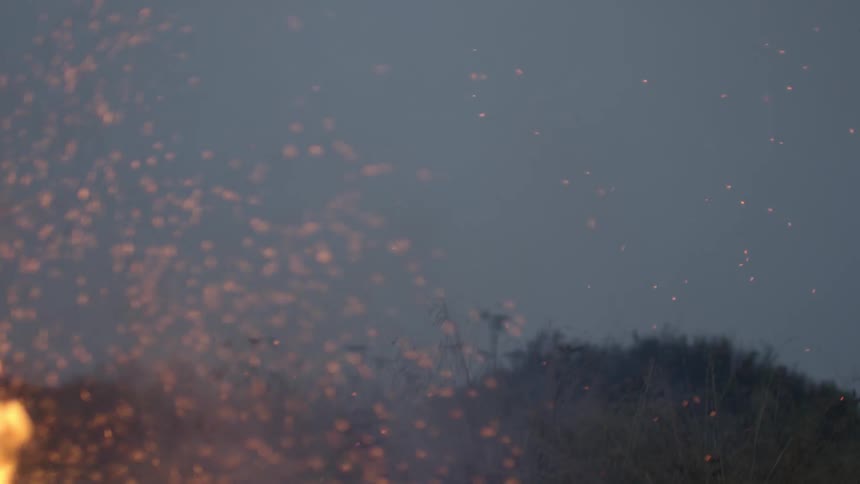 A fire in the wilderness shoots sparks into the air