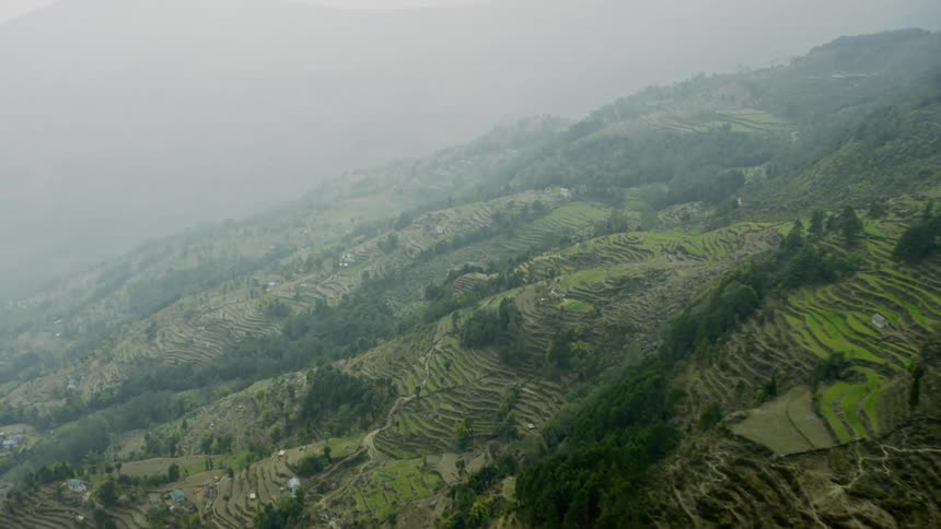 Haze hangs in the air around a farming village in a mountain range
