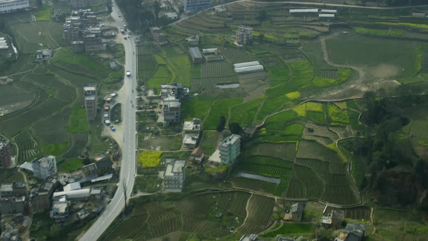 Vehicles travel on a road through a village