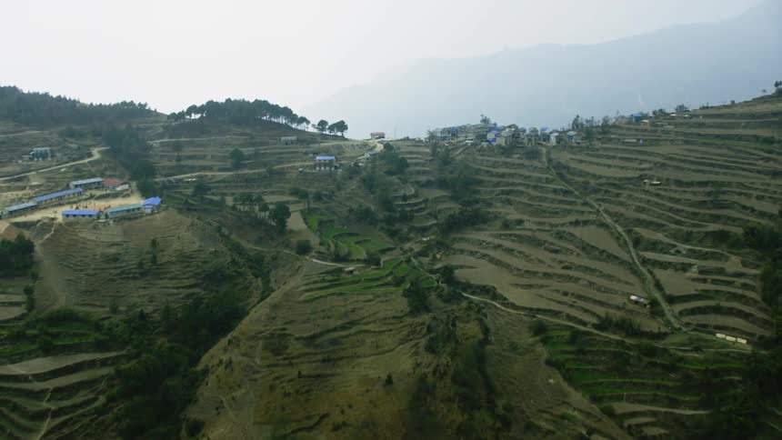 Haze hangs in the air around a farming village in a mountain range