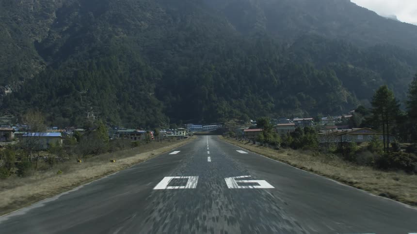 Buildings near a long stretch of road at the base of a mountain