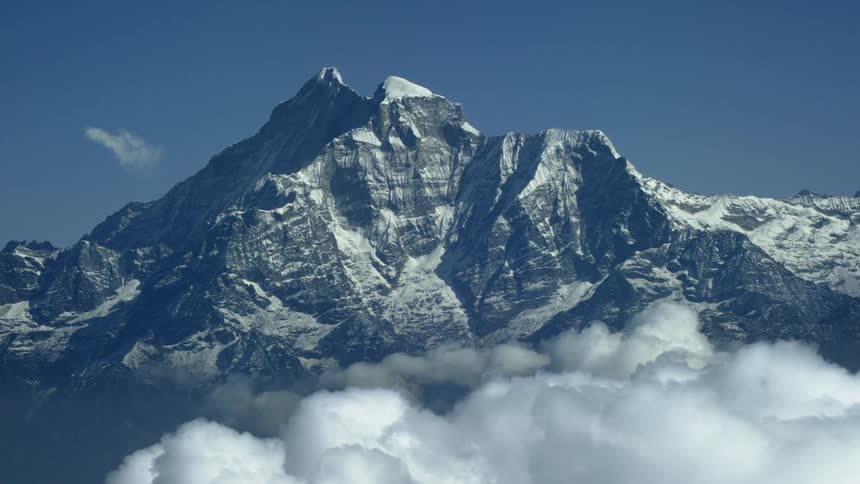 A snow covered mountain pierces through the clouds