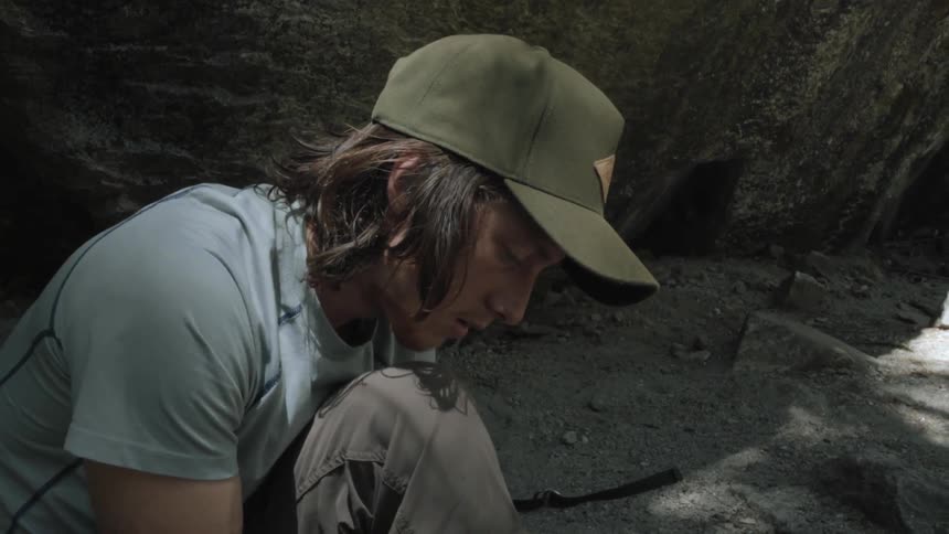 A man sits on the ground tying his shoe