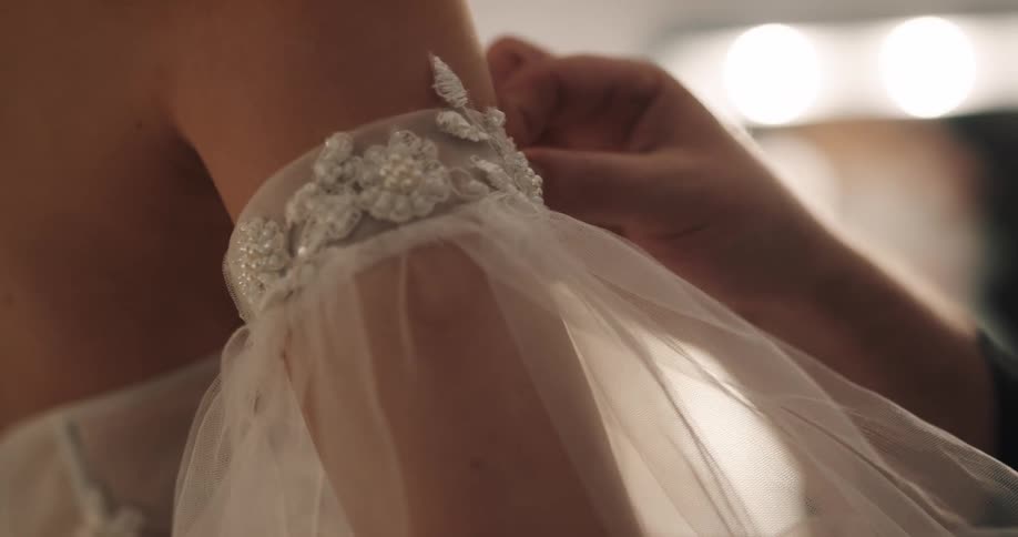 A man adjusts the sleeve on a womans arm in a dressing room