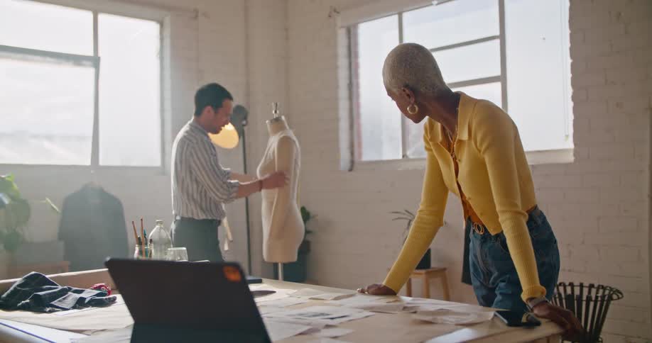 Designers discuss design referencing computer screen an outfit on mannequin