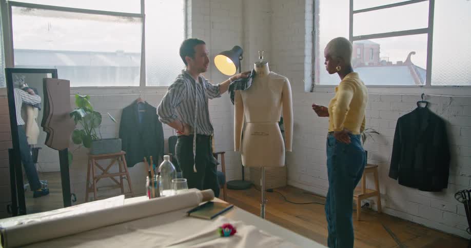 A man and a woman in a room with a mannequin with a wall and windows in the background