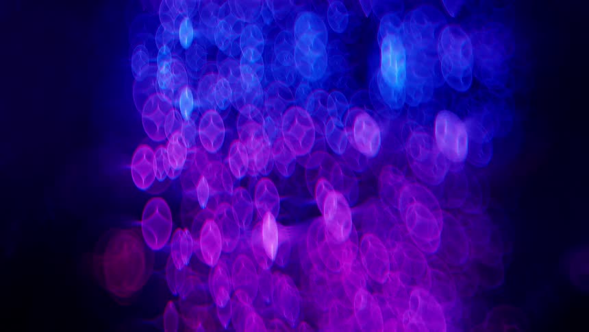 Purple and pink lights move up and down in the darkness