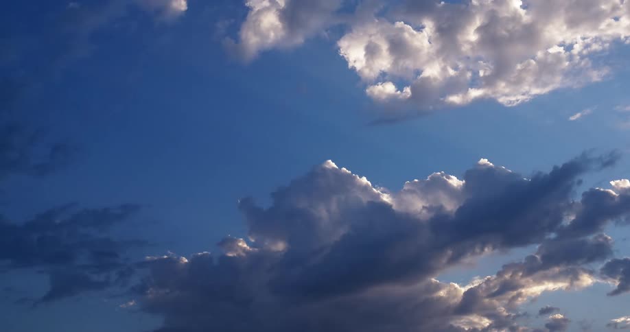 Cumulus clouds move across a blue sky