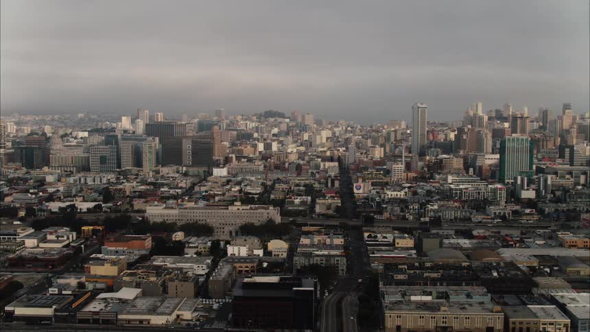 Aerial view of city skyline with apartment buildings and houses under cloudy sky
