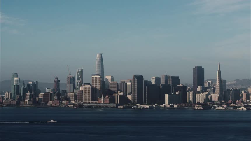 Tall city buildings along the downtown coast as a boat sails across the water