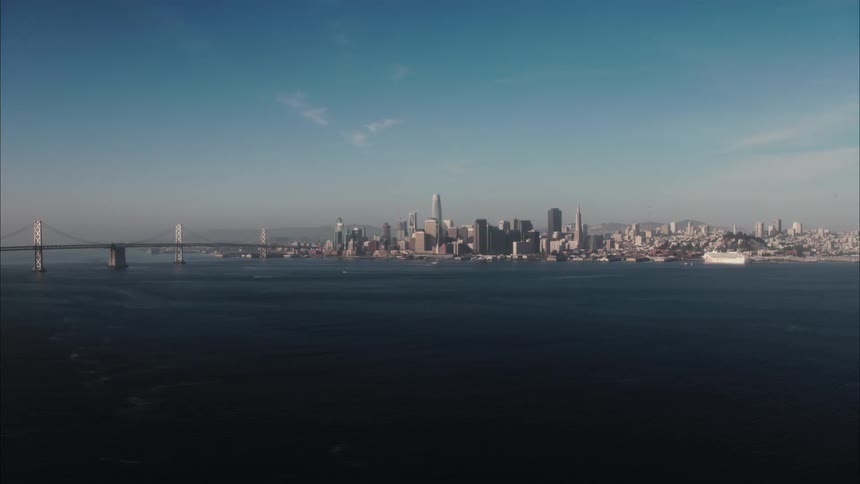 A city skyline with buildings skyscrapers and a bridge with the sky and clouds in the background