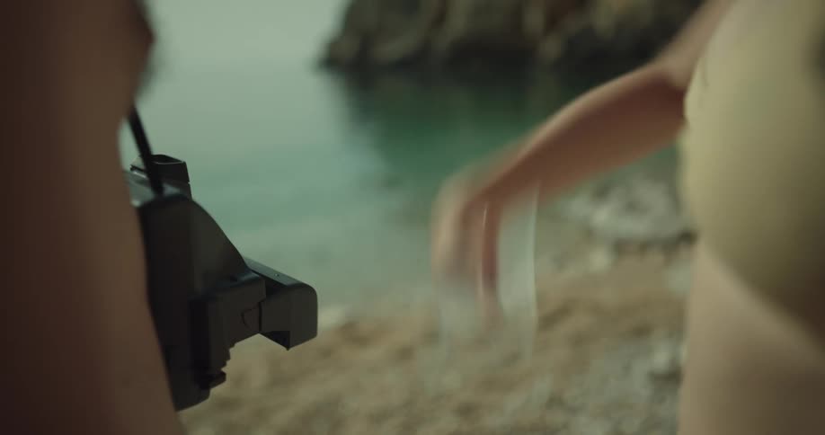 Woman shaking a polaroid picture near the beach