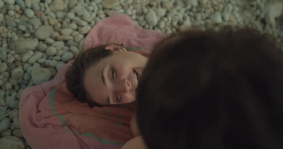 A man putting rocks onto his girlfriends stomach at the beach