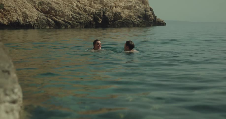 A couple swim in the water and kiss
