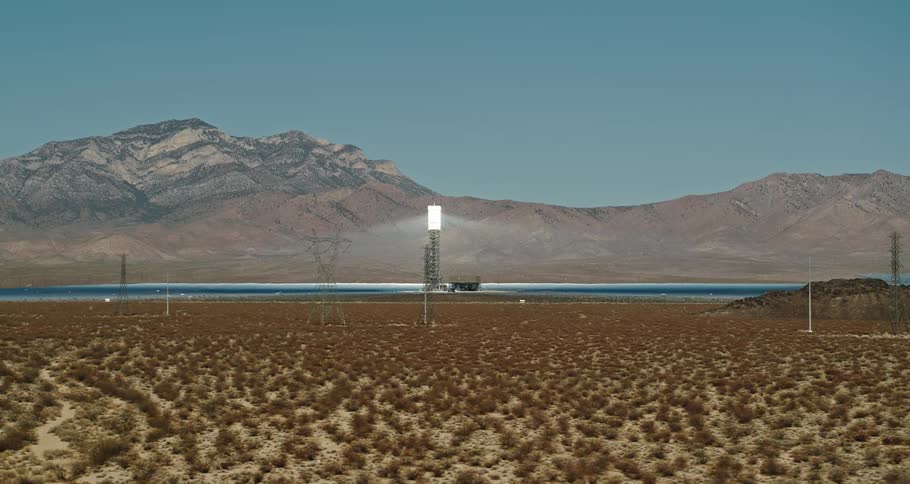 A view of a tower in the middle of solar panels in the desert