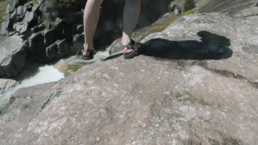 A man walks down some rocks on a cliff