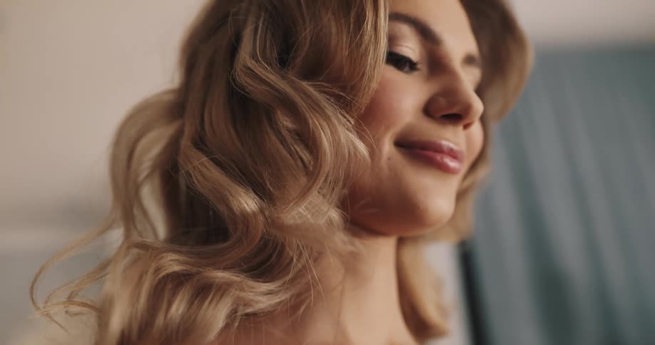 A model stands and smiles as a person puts makeup on her chest