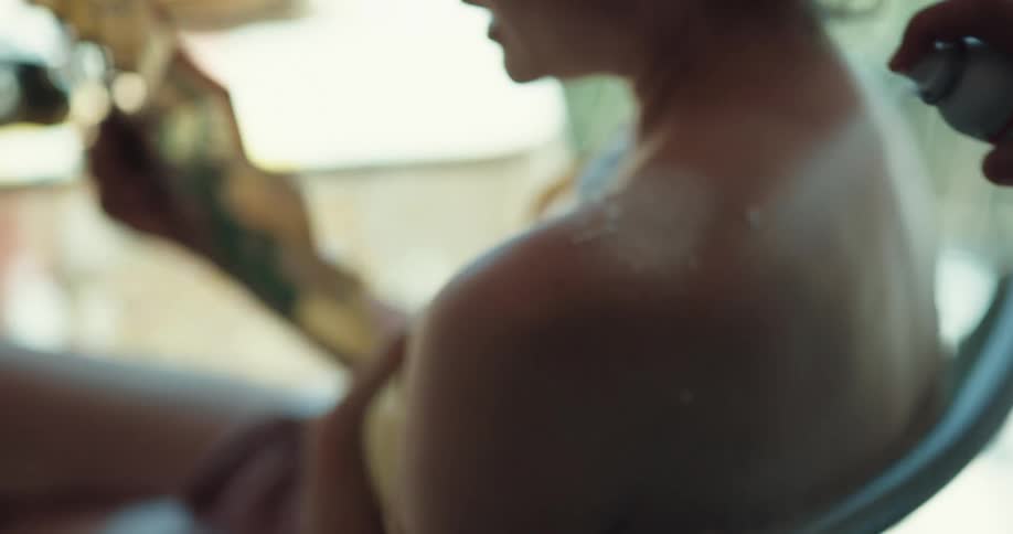 Young woman with burnt back sitting outdoors fanning herself