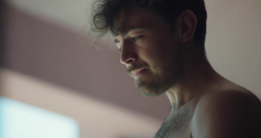 A man talks through tears while standing shirtless