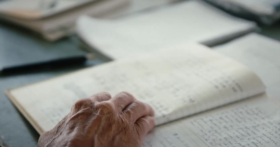 An elderly person is flipping through a notebook with writing in it