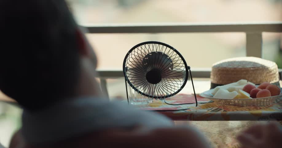 A man and woman use a rag and fan to cool off
