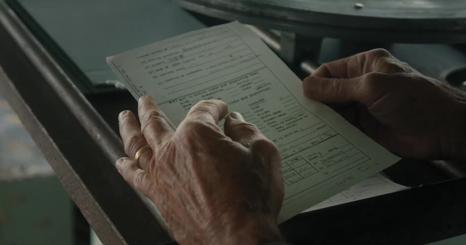 Hands hold a paper form with information filled in