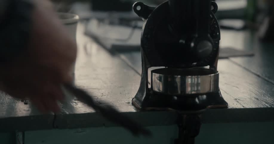 A person in a room painting a tool attached to a table with a paintbrush