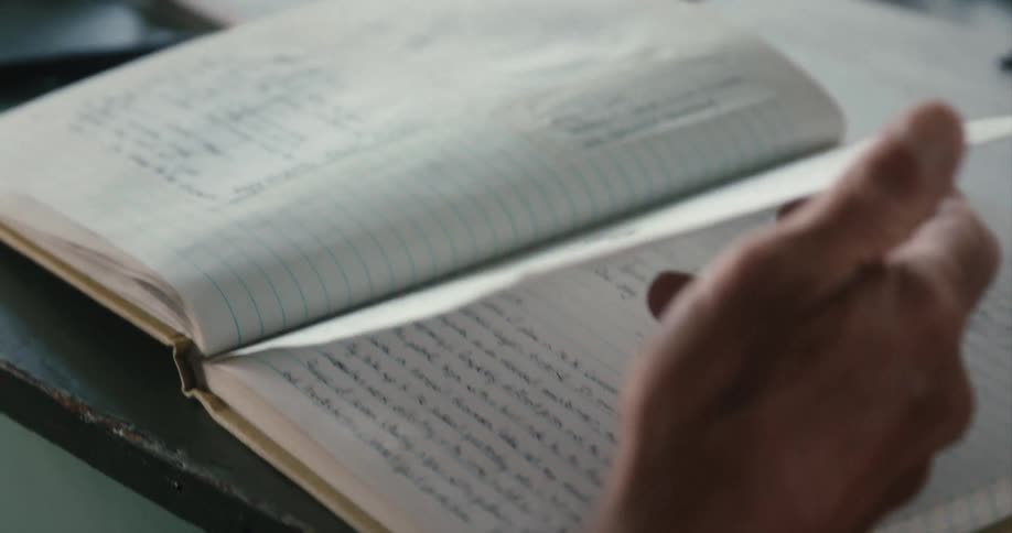 Man with watch and shirt turns over notebook pages