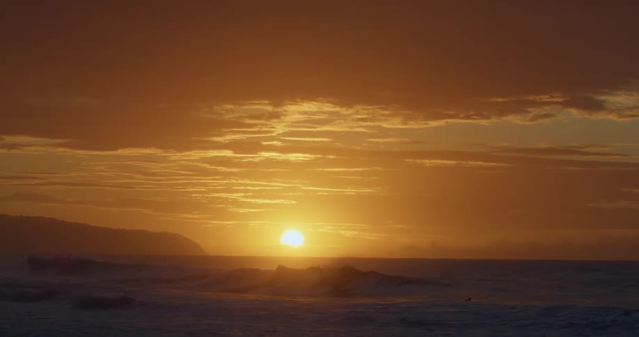 Ocean waves break against the beach at sunset