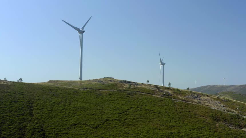 Hills with trees and wind turbines with the sky and clouds in the background