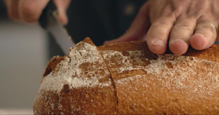Close up of man hands cutting crusty bread