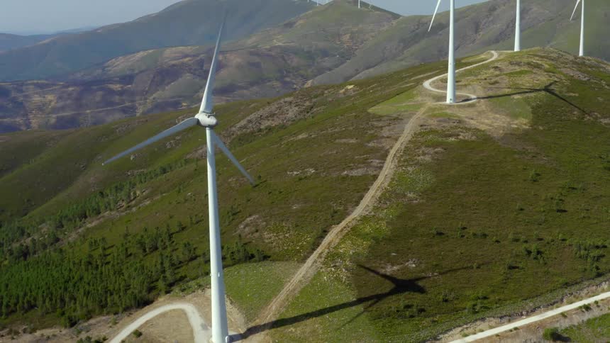 Aerial view of wind turbines on wind farm with mountains