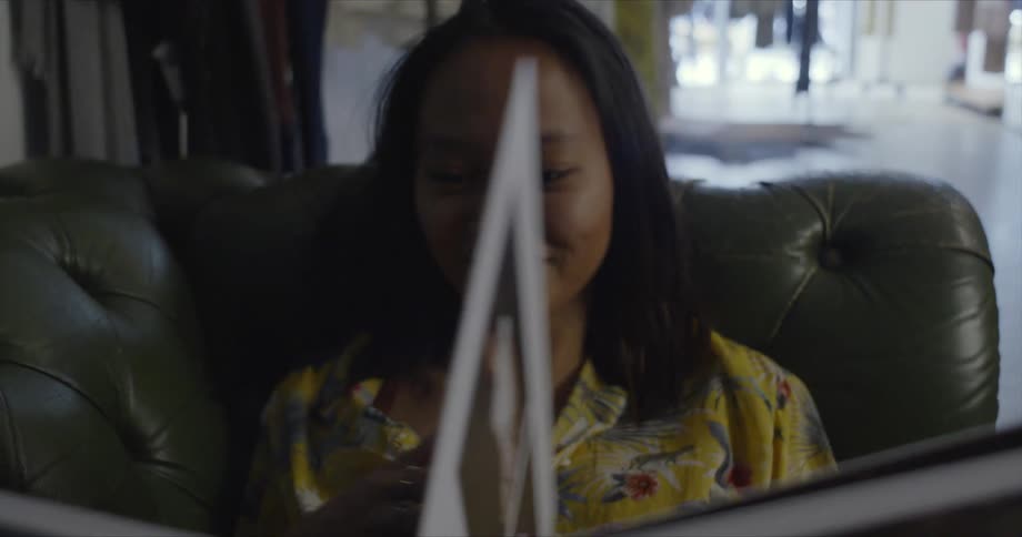 A woman sitting in a chair is smiling as she looks through a book