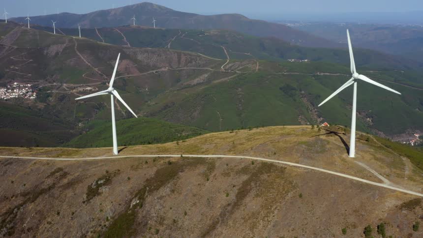 Wind turbines spin on the top of tall hills in the countryside