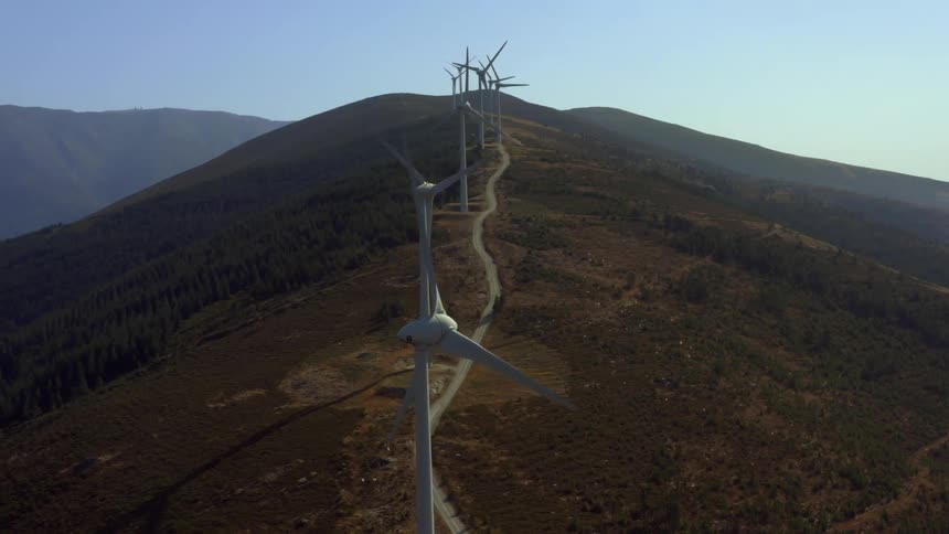 Aerial view of wind turbines spinning on a hill at morning