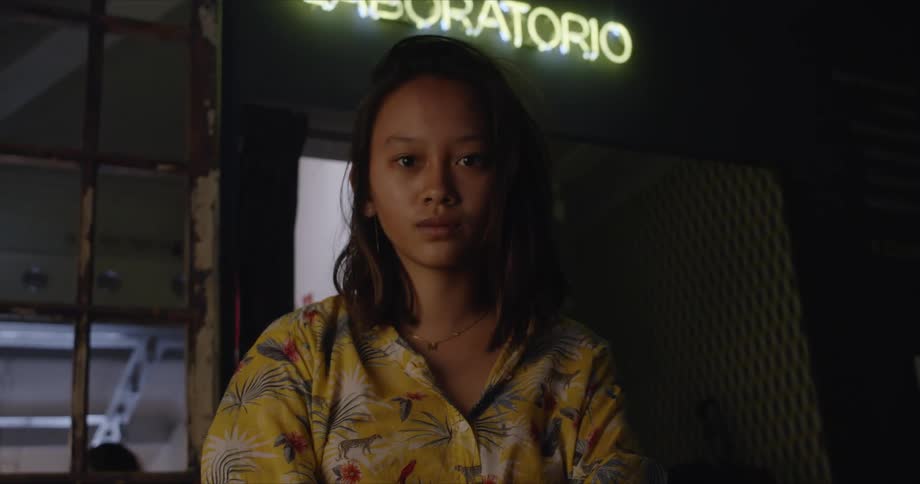Woman stands near neon sign announcing laboratory