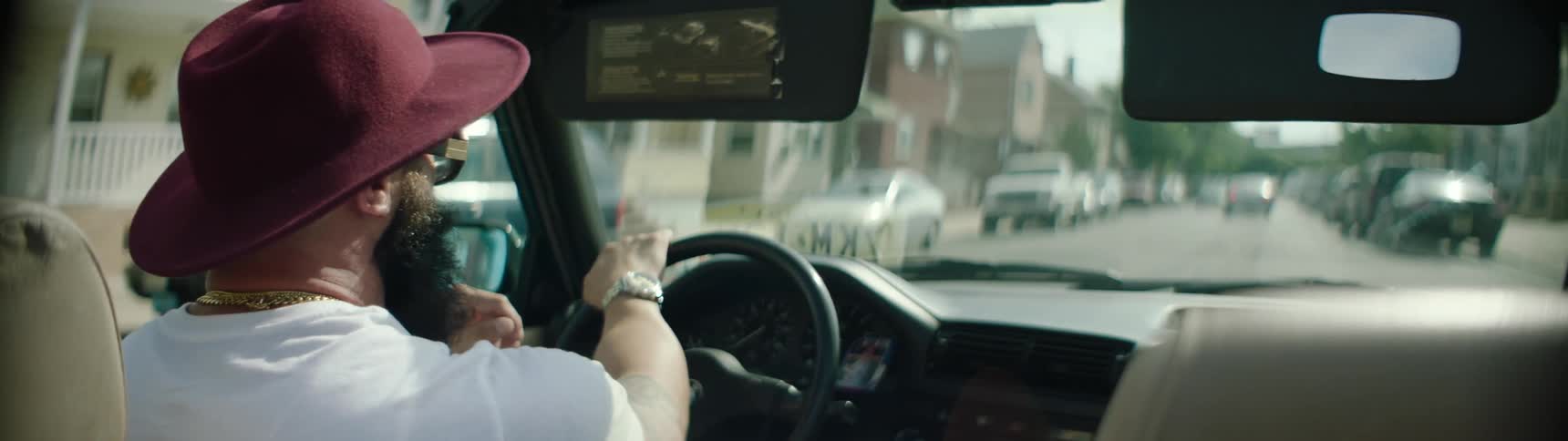A man wearing a red hat drives a car