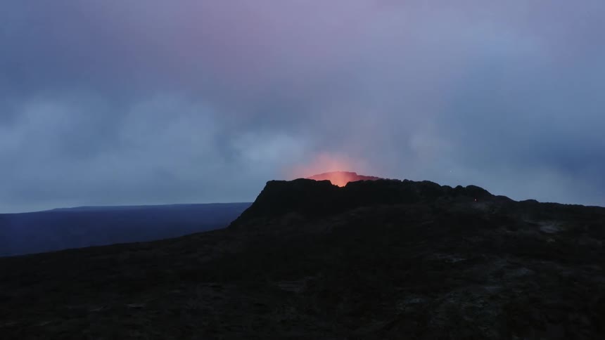 Orange lava bubbles up and glows in a volcano