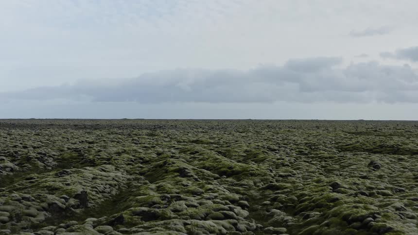 A landscape with rocks and moss with the sky and clouds in the background