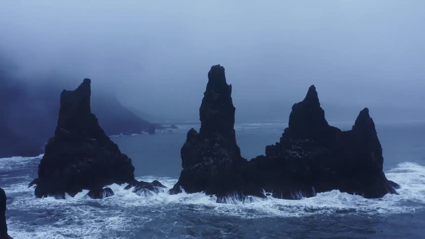 Aerial view of sharp vertical rock promontories over the ocean