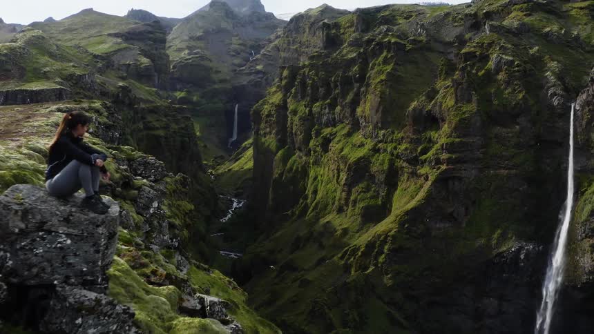 A waterfall flows down into a deep canyon with a river