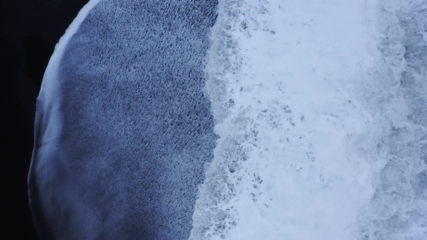 Ocean waves roll over a beach foaming as they move in